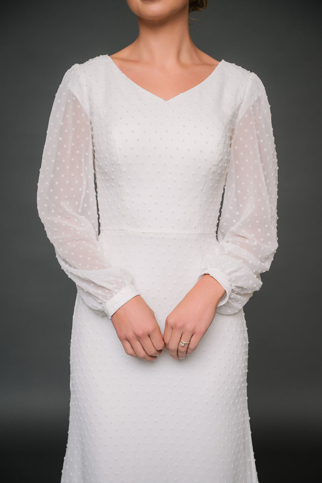 White textured modest wedding dress with long sleeves on a dark background