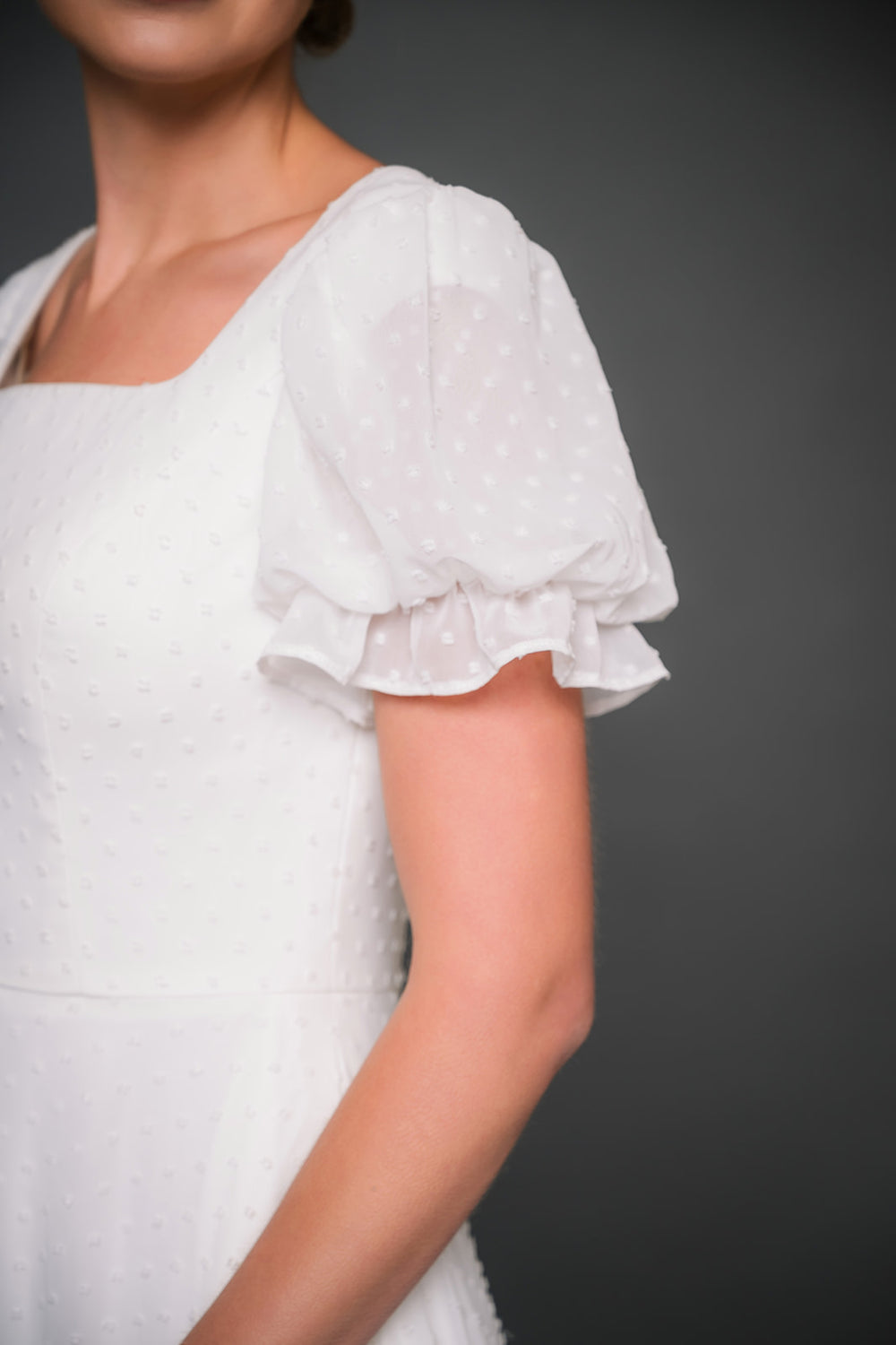 White modest wedding dress with ruffled sleeves on a dark background