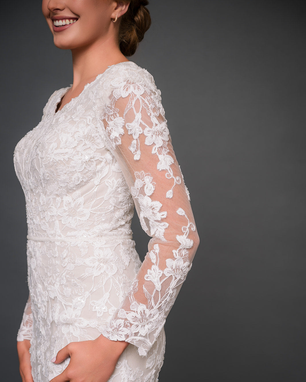 Ivory lace modest wedding dress with long sleeves on a dark background